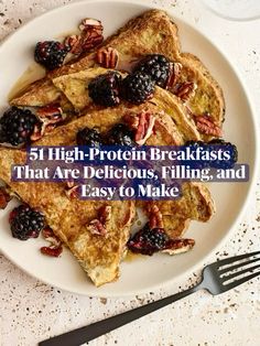 a white plate topped with french toast and berries next to a fork on top of a table