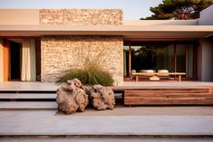 two large rocks sitting on the ground in front of a house with stairs leading up to it