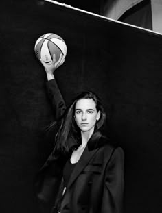 a woman holding a basketball up in the air with her right arm raised above her head