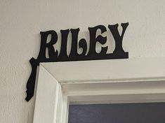 a black metal sign that says riley on the side of a white door with an open window