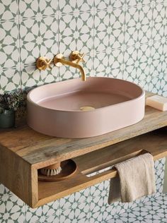 a bathroom sink sitting on top of a wooden counter next to a wall mounted faucet