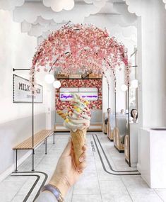 a person holding up an ice cream cone with cherry blossoms on the ceiling in front of them