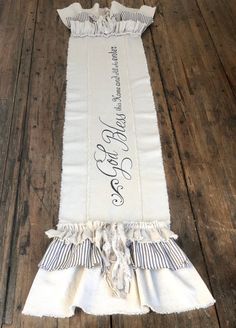 a white table runner with black and white ruffles on the edge, sitting on top of a wooden floor