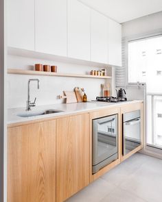 a kitchen with wooden cabinets and stainless steel appliances in the center, along with an open window