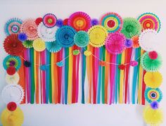 colorful paper flowers and streamers are hanging on the wall