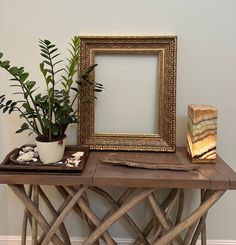 a wooden table topped with a potted plant next to a framed picture on top of it