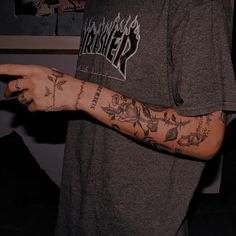 a man with tattoos on his arm pointing at something