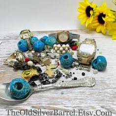 a table topped with lots of assorted jewelry and a silver spoon next to a sunflower