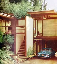 a car parked in front of a house with stairs leading up to the second floor