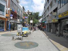 an empty city street with shops and stores on both sides, surrounded by tall buildings