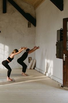 two women are doing yoga in an empty room with sunlight streaming through the windows and floor