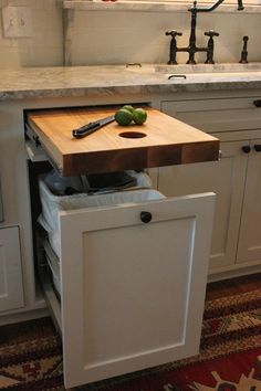 a kitchen with white cabinets and wooden cutting board