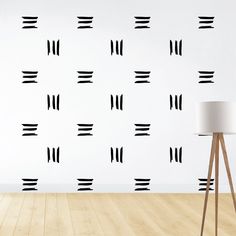 a wall that has some black and white designs on it, with a lamp next to it