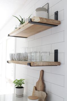 two wooden shelves filled with dishes on top of a kitchen counter next to a potted plant