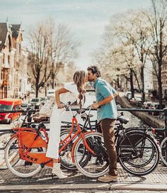 a man kissing a woman on the cheek while standing next to two bikes in front of them