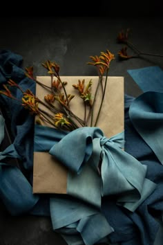 a gift wrapped in blue paper with flowers on it next to other wrapping material and branches