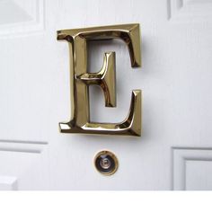 the letter e is painted gold on a white door