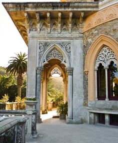 an archway leading into a garden with palm trees