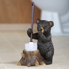 a bear figurine holding an umbrella on top of a tree stump with a toilet in the background