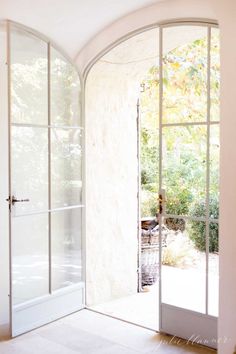 an open door leading into a white room with glass walls and doors on both sides