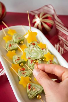 a person is picking up some food from a tray on a table with christmas decorations