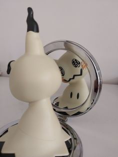 a white and black object is in the shape of a cat with its head inside a mirror