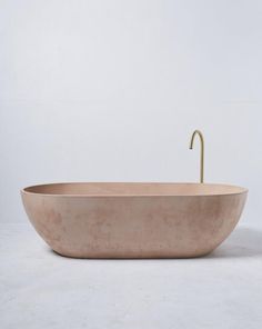 an oval bathtub with a gold faucet on the side and a white wall behind it