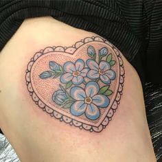 a heart shaped tattoo with blue flowers on it