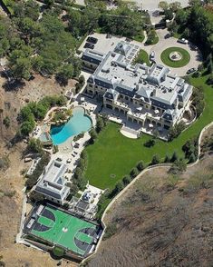 an aerial view of a large mansion with a swimming pool and tennis court in the foreground