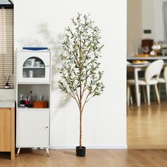 a small tree sitting in front of a cabinet next to a kitchen counter and dining room table