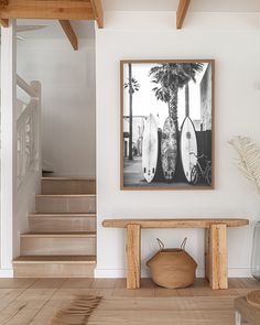 a wooden bench sitting in front of a painting on the wall next to some stairs