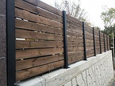 a wooden fence next to a brick wall with black metal bars on the top and bottom