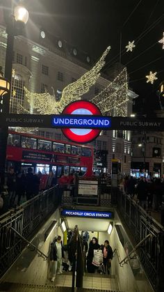 people are walking up an escalator in the city at christmas time with lights on