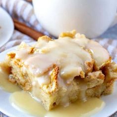 a white plate topped with cake covered in icing next to a glass of milk