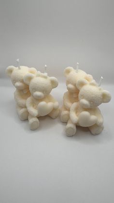 two white teddy bears sitting next to each other on top of a table with candles