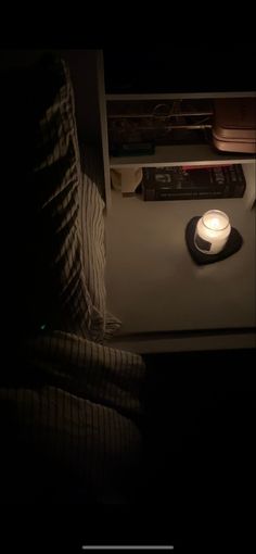 a remote control sitting on top of a table next to a lamp in the dark