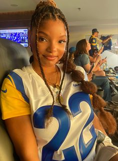 a young woman with braids sitting in an airplane wearing a jersey that reads 22