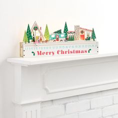 a white fireplace mantle with christmas decorations on top of it and a sign that says merry christmas