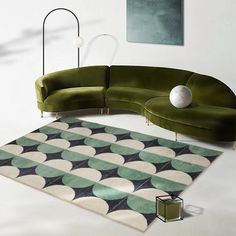 a green couch sitting on top of a white floor next to a rug and lamp