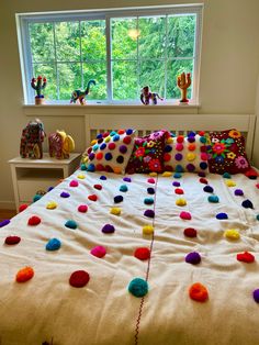 the bed is decorated with colorful pom - poms on it's covers