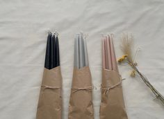 three candles are wrapped in brown paper and tied with twine on a white sheet