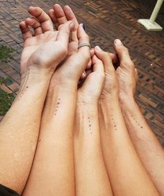 four people holding hands with small dots on their fingers