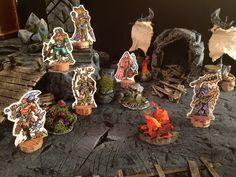 a table topped with lots of miniature figurines on top of wooden planks