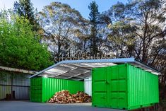 two green shipping containers sitting in the middle of a parking lot next to some trees