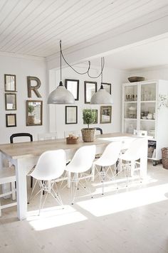 a dining room table with chairs and pictures on the wall in the backround