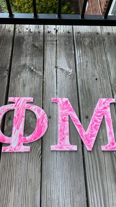 the word pm spelled with pink paint on a wooden deck next to a brick building