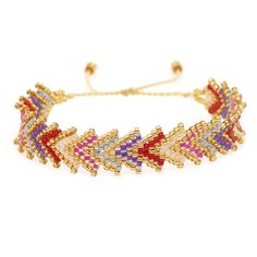 a multicolored bracelet with gold chains and beads on the sides, featuring an arrow design