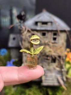 a tiny plant in a glass filled with water next to a small house and tree