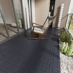 a rocking chair sitting on top of a patio next to a plant and glass doors