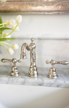 a bathroom sink with two faucets and flowers